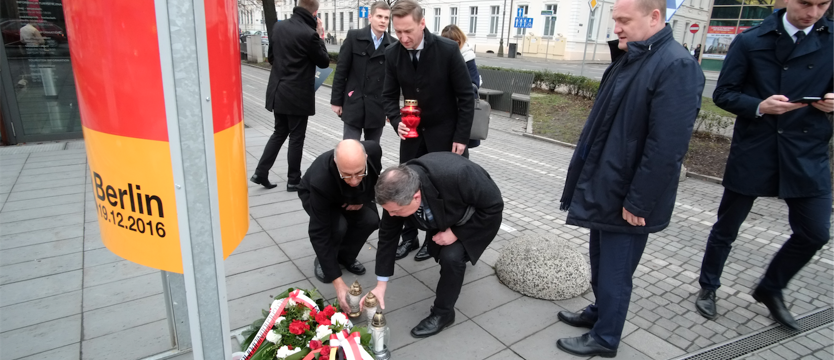 Kwiaty i znicze pod tablicą poświęconą zamachowi